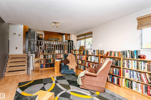 Hardwood-finish flooring throughout the room features extensive built-in shelving, providing abundant display and storage options - 18316 78 Avenue Nw, Edmonton, AB - Indoor