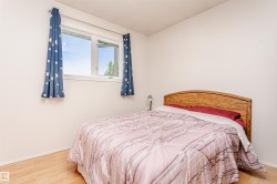 Bright bedroom featuring a large window, light wood-finish flooring, and a neutral wall color - 