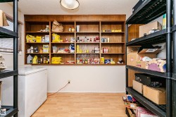Storage room featuring extensive built-in wooden shelving, wood-finish flooring, and additional black shelving units - 