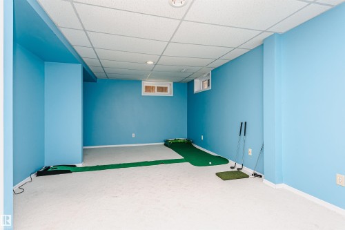 Spacious room featuring light blue walls and white trim, white drop ceiling with recessed lighting, and white carpet flooring - 18316 78 Avenue Nw, Edmonton, AB - Indoor