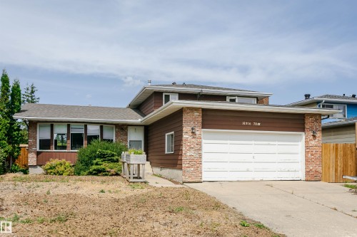 Brown siding home featuring a brick facade, white garage door, and a multi-paned bay window - 18316 78 Avenue Nw, Edmonton, AB - Outdoor