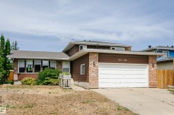 Brown siding home featuring a brick facade, white garage door, and a multi-paned bay window - 