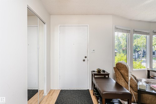 Entryway featuring a solid white door with black hardware, wood-finish flooring, and mirrored closet doors - 18316 78 Avenue Nw, Edmonton, AB - Indoor Photo Showing Other Room