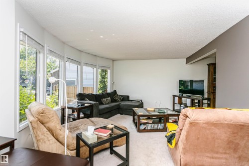 Living room featuring a curved wall of multiple windows, a neutral color palette, and light-toned carpeting - 18316 78 Avenue Nw, Edmonton, AB - Indoor Photo Showing Living Room