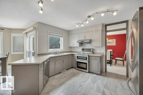 Kitchen featuring light gray base cabinetry, white upper cabinetry, and a white subway tile backsplash - 568 Buchanan Road Nw, Edmonton, AB - Indoor Photo Showing Kitchen With Double Sink