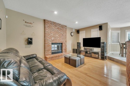 Living room featuring a brick wood burning fireplace & hardwood floor - 568 Buchanan Road Nw, Edmonton, AB - Indoor Photo Showing Living Room With Fireplace