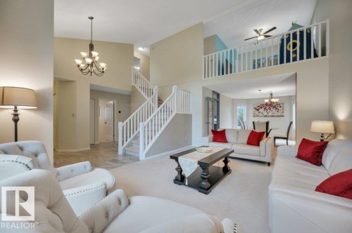 Spacious living area featuring high ceilings, a grand staircase with white railings, and a second-story loft area overlooking the living room - 568 Buchanan Road Nw, Edmonton, AB - Indoor Photo Showing Living Room
