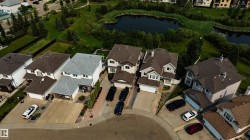 Aerial perspective featuring residential properties with manicured landscaping and paved driveways - 