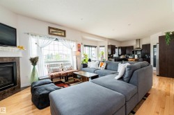 Open-concept living space featuring wood-finish flooring, a fireplace with a tile surround and mantel, and a large window - 