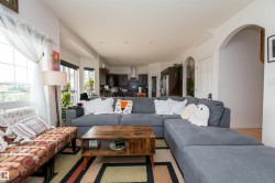 Open-concept living area with light-toned walls and wood-finish flooring - 