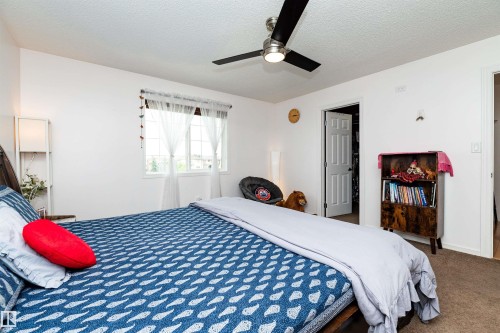 Bedroom featuring a ceiling fan with integrated lighting, a window with white trim, and neutral-toned carpeting - 715 Wildwood Point(E) Nw, Edmonton, AB - Indoor Photo Showing Bedroom