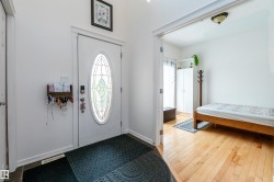 Entryway featuring a white door with an oval stained-glass insert, slate tile flooring, and light wood-finish flooring - 