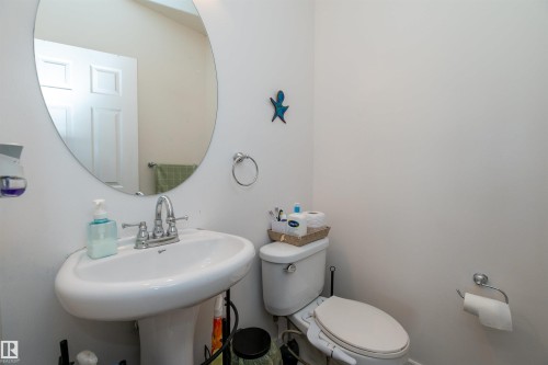 Pedestal sink with a chrome faucet, oval mirror, and white walls - 715 Wildwood Point(E) Nw, Edmonton, AB - Indoor Photo Showing Bathroom