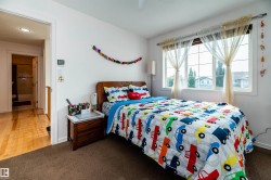 Bright bedroom featuring a large window with multiple panes, recessed lighting, and brown carpet flooring - 