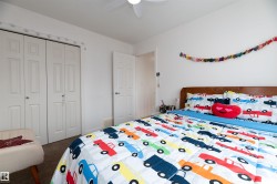 Bedroom featuring bi-fold closet doors, a ceiling fan, and a wood-finish headboard - 