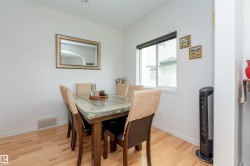 Dining area featuring wood-finish flooring, a window with a black roller shade, and white baseboards - 