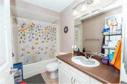 Full bathroom featuring a white vanity with a brown countertop, a built-in sink, a wall-mounted mirror, and a three-light fixture - 