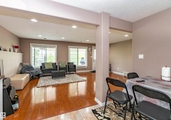 Open-concept living area featuring wood-finish flooring, recessed lighting, and multiple windows - 
