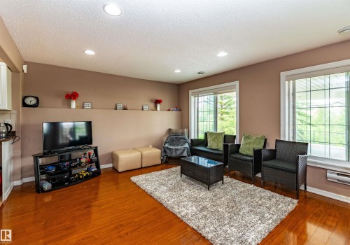 Spacious interior featuring wood-finish flooring, recessed lighting, and large windows with white trim - 715 Wildwood Point(E) Nw, Edmonton, AB - Indoor Photo Showing Living Room