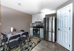 Kitchen area featuring white cabinetry, stainless steel appliances, dark countertops, and tile flooring - 