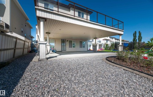 Elevated deck with glass panel railing above a covered concrete patio supported by decorative columns - 715 Wildwood Point(E) Nw, Edmonton, AB - Outdoor