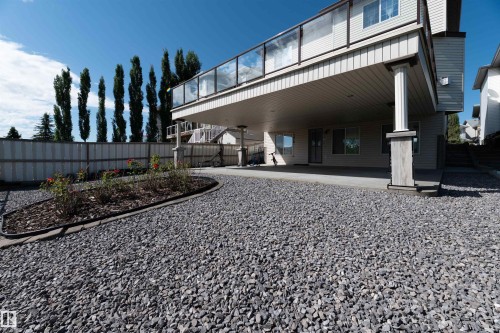 Expansive gravel patio area featuring a raised deck with glass railings and a covered concrete patio below - 715 Wildwood Point(E) Nw, Edmonton, AB - Outdoor With Deck Patio Veranda