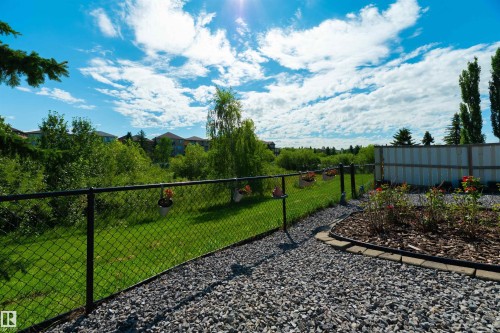 Expansive outdoor space featuring a gravel pathway, chain-link fencing, a mulched garden bed, and a verdant lawn - 715 Wildwood Point(E) Nw, Edmonton, AB - Outdoor With View