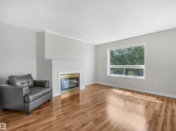 Living area featuring a fireplace with a brass-toned insert, wood-finish flooring, and a large window - 