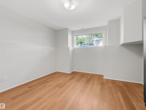 Room featuring wood-finish flooring, white baseboards, and light gray walls - #2 3311 58 St Nw, Edmonton, AB - Indoor Photo Showing Other Room