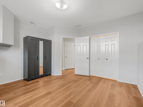 Spacious room featuring wood-finish flooring, white paneled doors, and a ceiling-mounted light fixture - #2 3311 58 St Nw, Edmonton, AB - Indoor Photo Showing Other Room