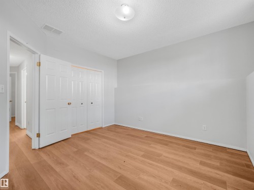 Spacious room featuring light wood-finish flooring, white bi-fold closet doors, and light gray painted walls - #2 3311 58 St Nw, Edmonton, AB - Indoor Photo Showing Other Room