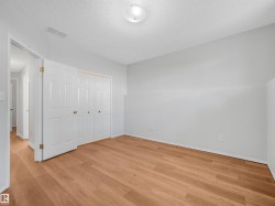 Spacious room featuring light wood-finish flooring, white bi-fold closet doors, and light gray painted walls - 
