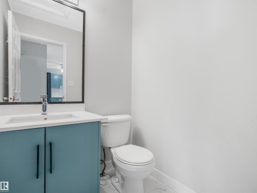 Powder room featuring a blue vanity with a white countertop, modern sink, and chrome faucet - #2 3311 58 St Nw, Edmonton, AB - Indoor Photo Showing Bathroom