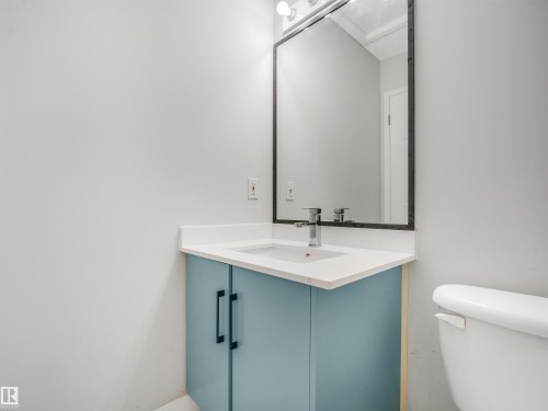 Vanity area featuring a light blue cabinet with black hardware, white countertop, and a rectangular sink with a chrome faucet - #2 3311 58 St Nw, Edmonton, AB - Indoor Photo Showing Bathroom