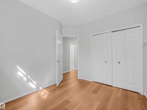 Neutral wall paint complemented by wood-finish flooring - #2 3311 58 St Nw, Edmonton, AB - Indoor Photo Showing Other Room
