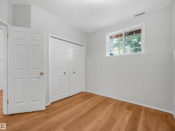 Room featuring wood-finish flooring, white walls, and a white bi-fold closet - 