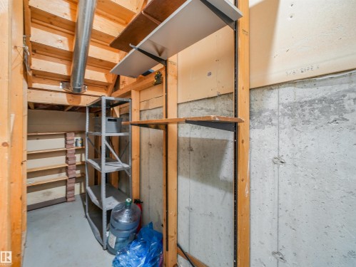 Storage area featuring exposed wood framing, concrete walls, built-in shelving, and a metal utility rack - #2 3311 58 St Nw, Edmonton, AB - Indoor