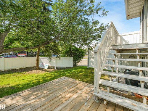 Rear wood-finish deck with wooden steps, surrounded by a green lawn and mature trees - #2 3311 58 St Nw, Edmonton, AB - Outdoor With Deck Patio Veranda