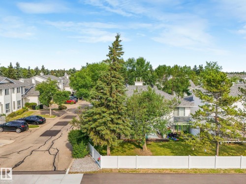 Townhome community featuring white exterior finishes, gray shingle roofs, and mature landscaping - #2 3311 58 St Nw, Edmonton, AB - Outdoor