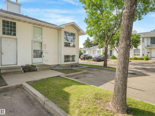 White siding exterior with multiple windows, featuring an entryway with a white door and concrete steps - #2 3311 58 St Nw, Edmonton, AB - Outdoor