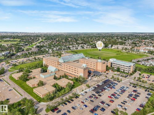 Large institutional building with expansive paved parking areas and surrounding green spaces - #2 3311 58 St Nw, Edmonton, AB - Outdoor With View