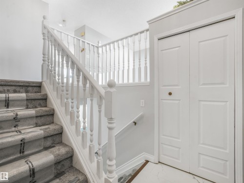 Carpeted staircase with white balusters and newel posts - #2 3311 58 St Nw, Edmonton, AB - Indoor Photo Showing Other Room