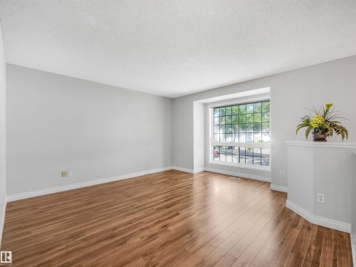 Bright interior room featuring wood-finish flooring, light gray walls, and white baseboards - #2 3311 58 St Nw, Edmonton, AB - Indoor Photo Showing Other Room