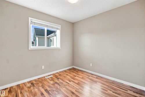 Hardwood-finish flooring complementing light neutral wall tones - 1328 80 Street Sw, Edmonton, AB - Indoor Photo Showing Other Room