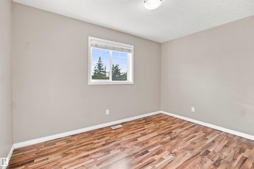 Interior room featuring wood-finish flooring, light neutral-toned walls, and white trim - 1328 80 Street Sw, Edmonton, AB - Indoor Photo Showing Other Room