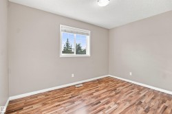 Interior room featuring wood-finish flooring, light neutral-toned walls, and white trim - 