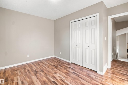 Interior space featuring wood-finish flooring, light neutral wall paint, and white bi-fold closet doors - 1328 80 Street Sw, Edmonton, AB - Indoor Photo Showing Other Room
