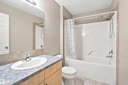 Bathroom featuring a bathtub with an integrated shower, chrome fixtures, a vanity with an undermount sink, a large wall mirror, and tile flooring - 