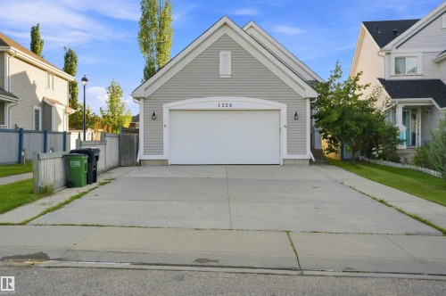 Light gray siding exterior with a white garage door featuring an arched transom - 1328 80 Street Sw, Edmonton, AB - Outdoor