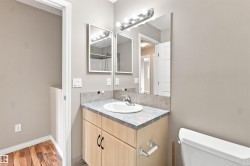 Bathroom vanity featuring a light wood-finish cabinet with black hardware, a laminate countertop, and an integrated white basin - 